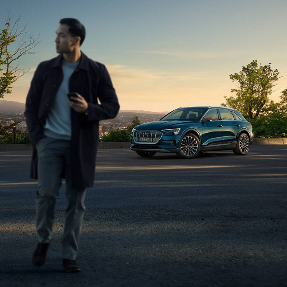 Propriétaire d’un véhicule Audi debout devant son Audi e-tron.
