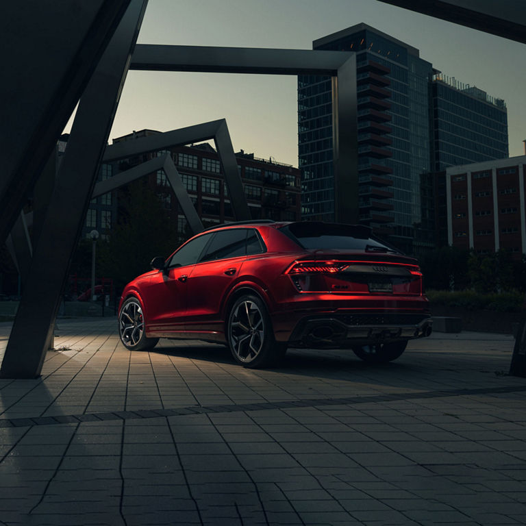 Three-quarter rear view of a red Audi RS Q8 parked.        