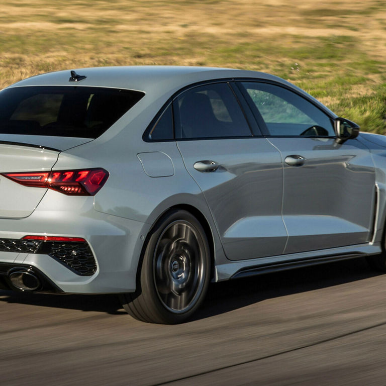 Vue de trois quarts arrière d’une Audi RS 3 grise en mouvement. 