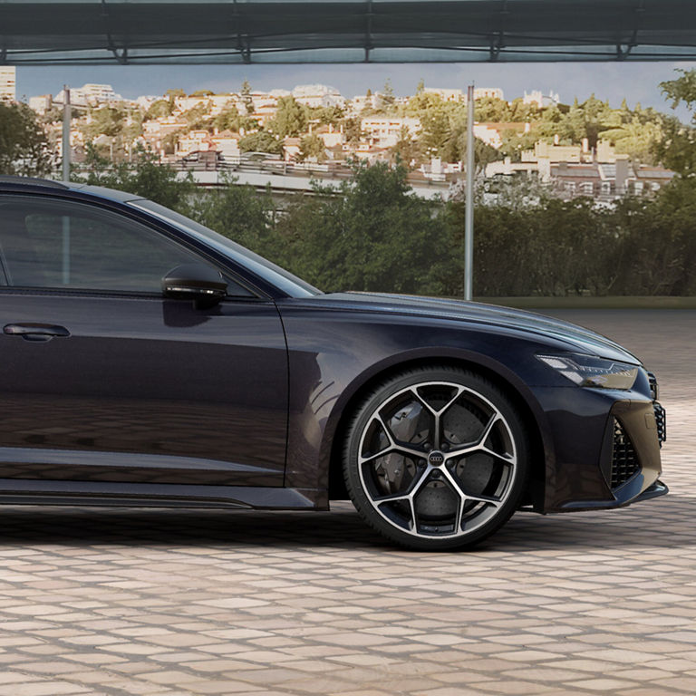 Profil latéral d’une Audi RS 6 Avant noire stationnée sur une rue pavée.