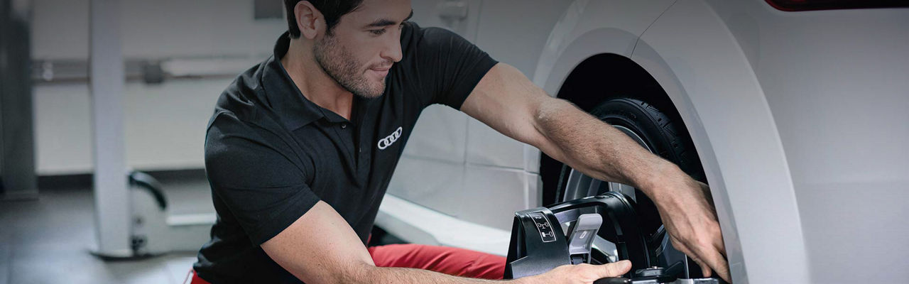 Un technicien Audi en train d’installer une roue sur un véhicule.