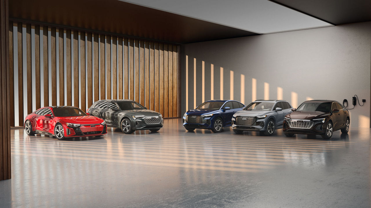 A lineup of Audi e-tron vehicles parked in a modern building. 