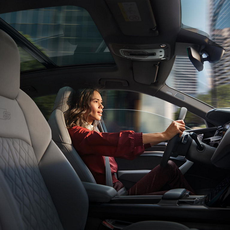 A close-up photo of a woman behind the wheel of an Audi e-tron.