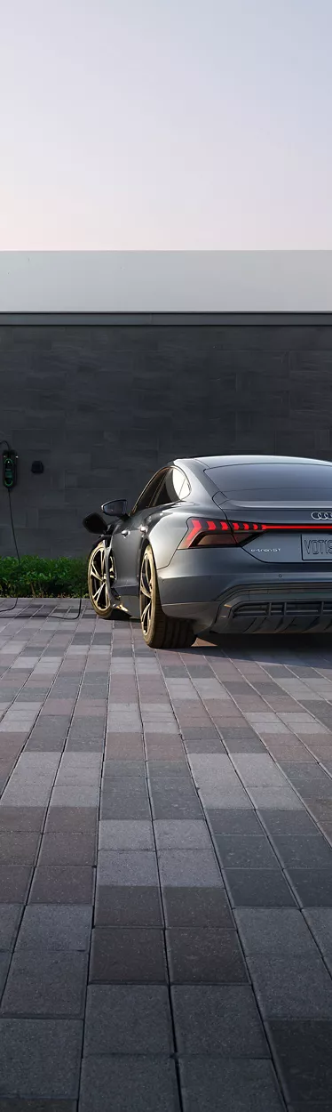 A wide-shot photo of the back of an Audi e-tron GT parked in residential driveway.