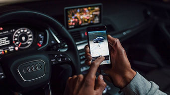 Close-up of a person using the myAudi app on their smartphone while seating in an Audi vehicle.