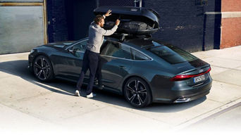 A person open up the roof box bag attached to the roof of an Audi vehicle.
