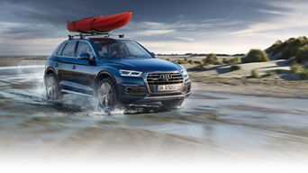 Front view of an Audi vehicle accelerating with a kayak on the roof.