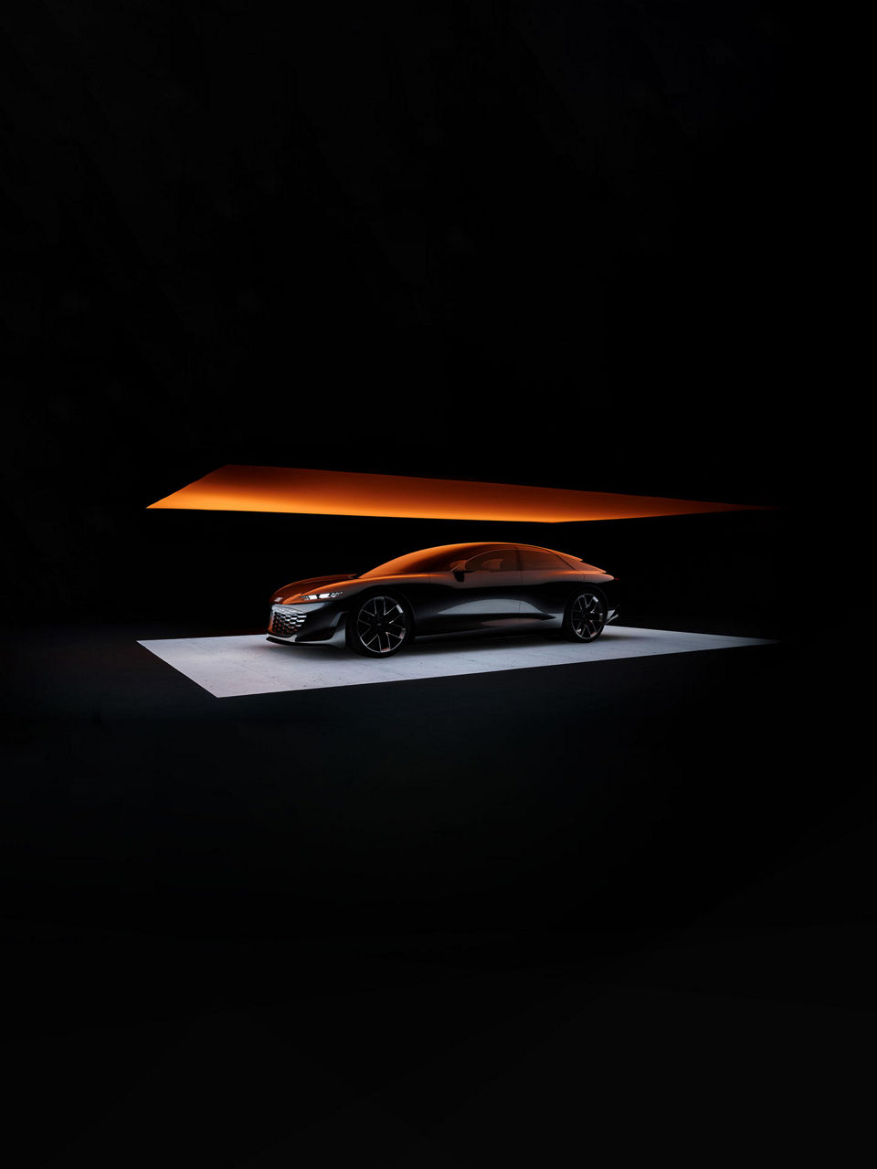 Une voiture conceptuelle Audi stationnée sur une scène argent dans une pièce sombre illuminée par un néon. 