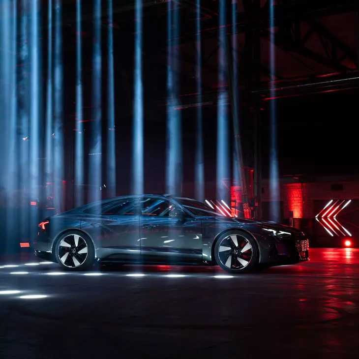 Une Audi RS e-tron GT stationnée dans une pièce sombre illuminée par des stroboscopes.