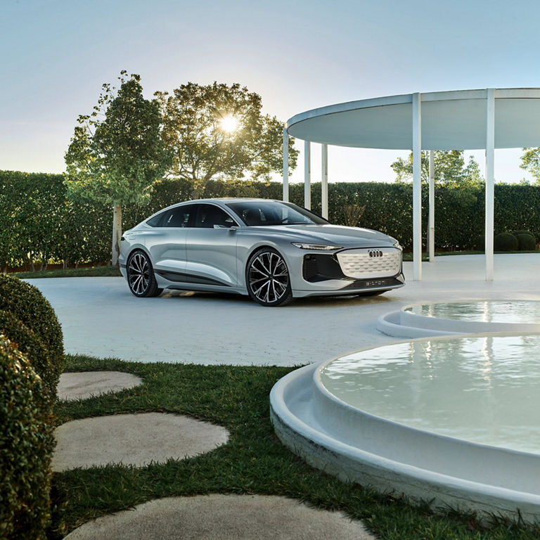 Photo of an Audi A6 e-tron concept car parked outside in an outdoor garden near reflection pools.