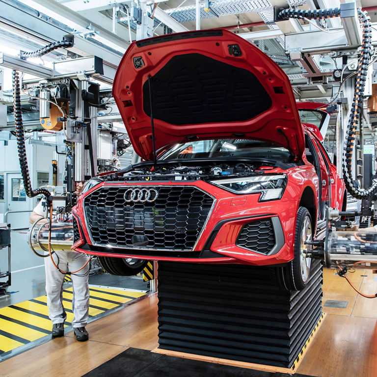 Photo of workers in an Audi factory assembling an Audi vehicle.