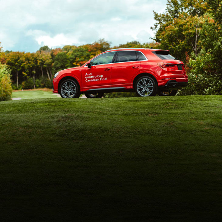 Side-view of an Audi vehicle with Audi Quattro Cup decal on side body parked on a golf course. 