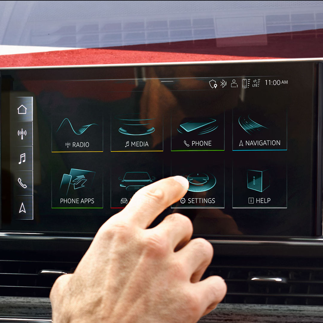 A close-up photo of someone's hand accessing touch-screen of the Audi MMI display inside an Audi vehicle.