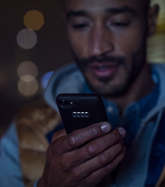 Gros plan sur une personne utilisant son smartphone avec une coque de téléphone de marque Audi.