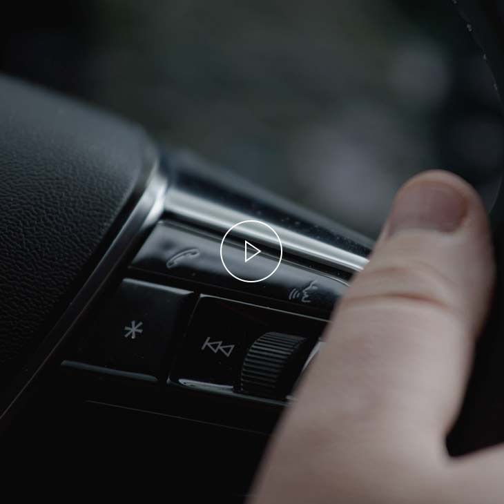  Close-up photo of a person's thumb resting on the talk button on the multifunction steering wheel inside an Audi vehicle. 