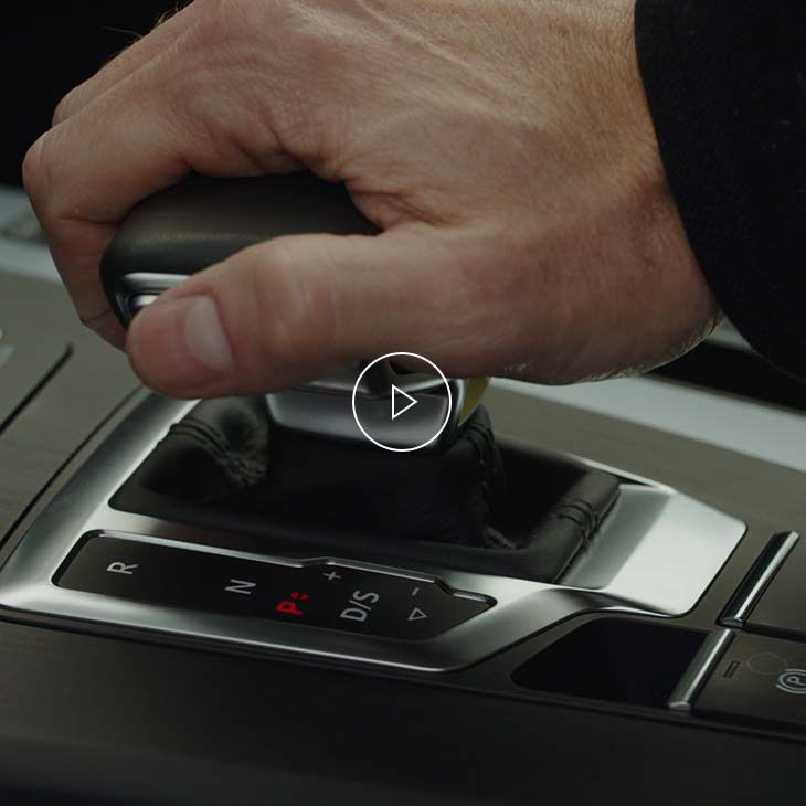  Close-up photo of a person's hand resting on the gear shift inside an Audi vehicle.