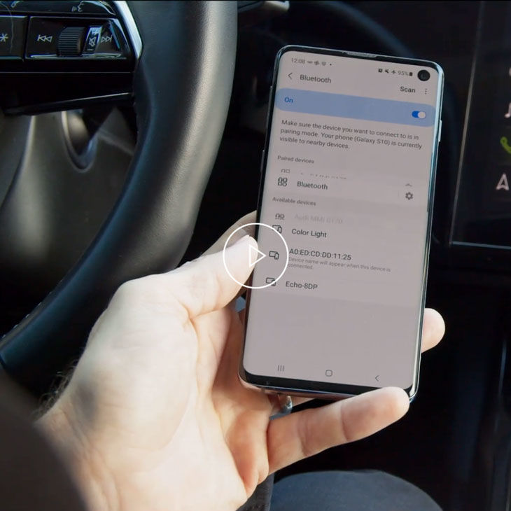 Close-up photo of a person pairing their mobile phone to their Audi vehicle with Bluetooth. 