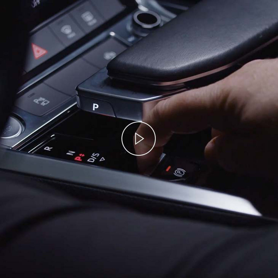 Photo of a person activating the electronic parking brake of an Audi vehicle.