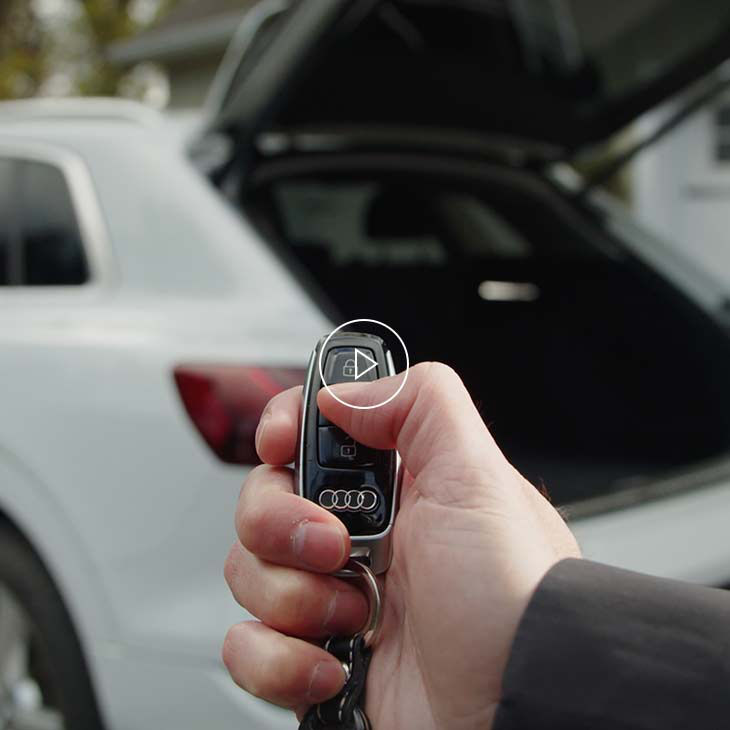  Photo of a person using the multifunction key to operate the power rear tailgate of an Audi vehicle. 