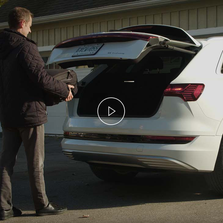 Photo d’une personne déposant une valise dans le compartiment à bagages mains libres d’un véhicule Audi.