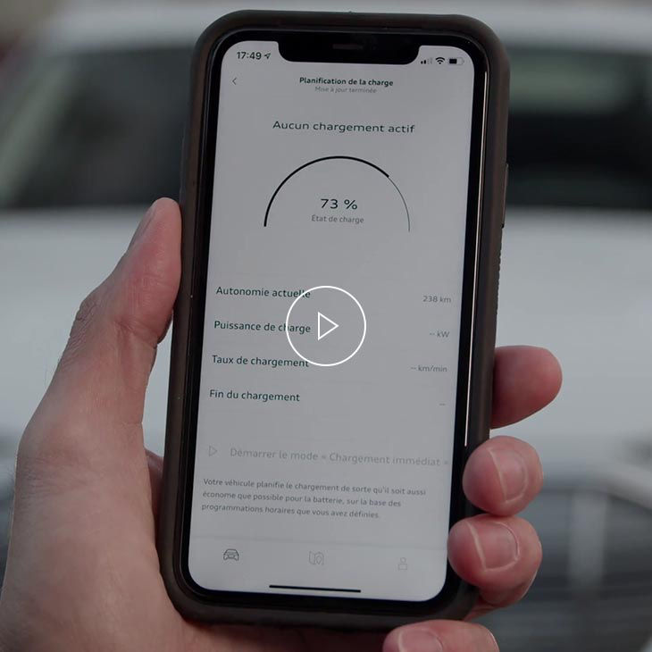 Photo d’une personne tenant un téléphone cellulaire présentant l’interface de recharge de Chargement av myAudi. 