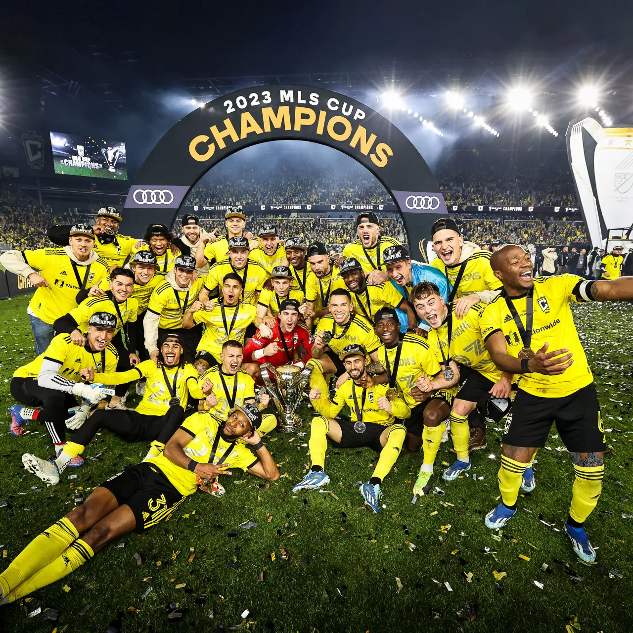 Soccer team taking a picture while celebrating win in stadium.