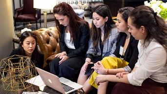 A group of women sitting around a laptop.