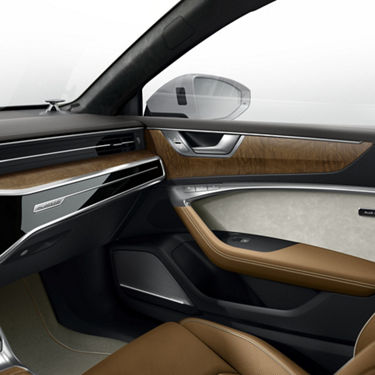 Interior shot of an Audi A7 Sportback with Cognac Brown door armrests, Alabaster White door trim inserts, and fine grain ash wood inlays. 