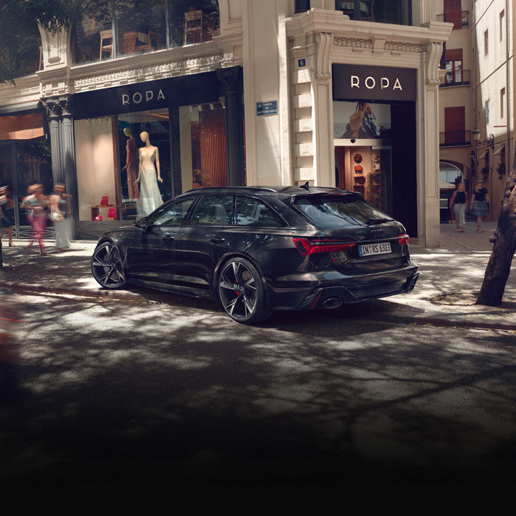 Three-quarter rear view of a black Audi RS 6 parked on a city street.