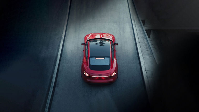  Bird's eye view of a red Audi RS e-tron GT driving on a dark road.