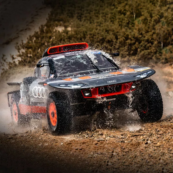 An Audi RS Q-etron tackles a muddy puddle during the 2022 Dakar Rally.