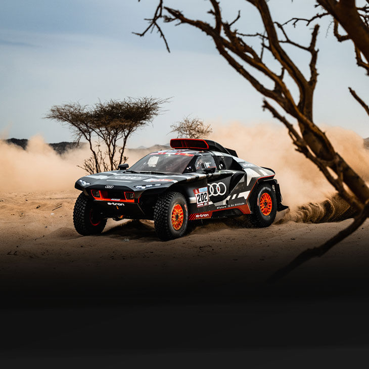 An Audi RS Q e-tron kicking up dust on the road during the 2022 Dakar Rally. 