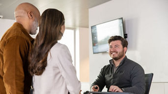 An Audi dealer speaking to two customers in an Audi dealership.