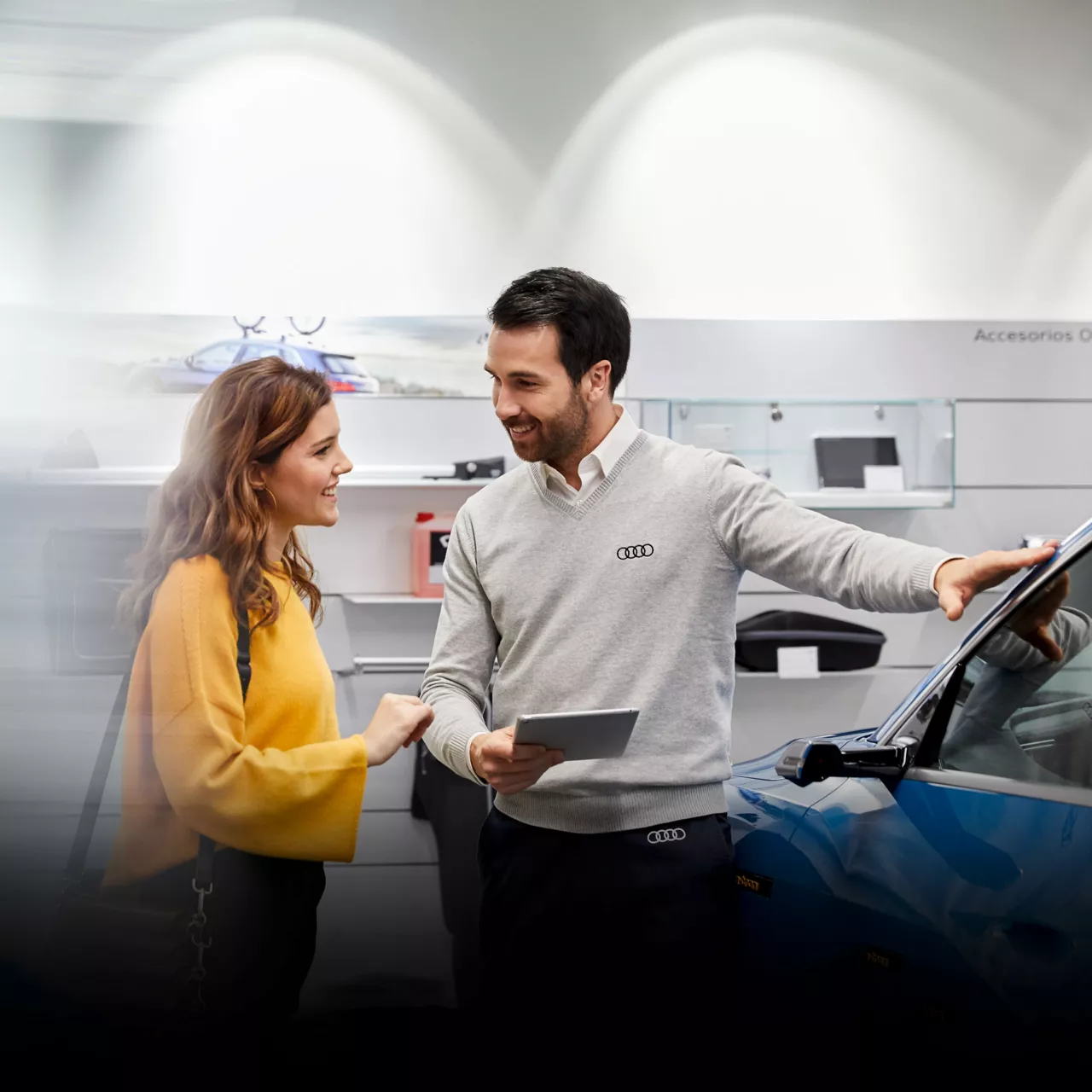 An Audi dealer showing a vehicle to a young woman. 