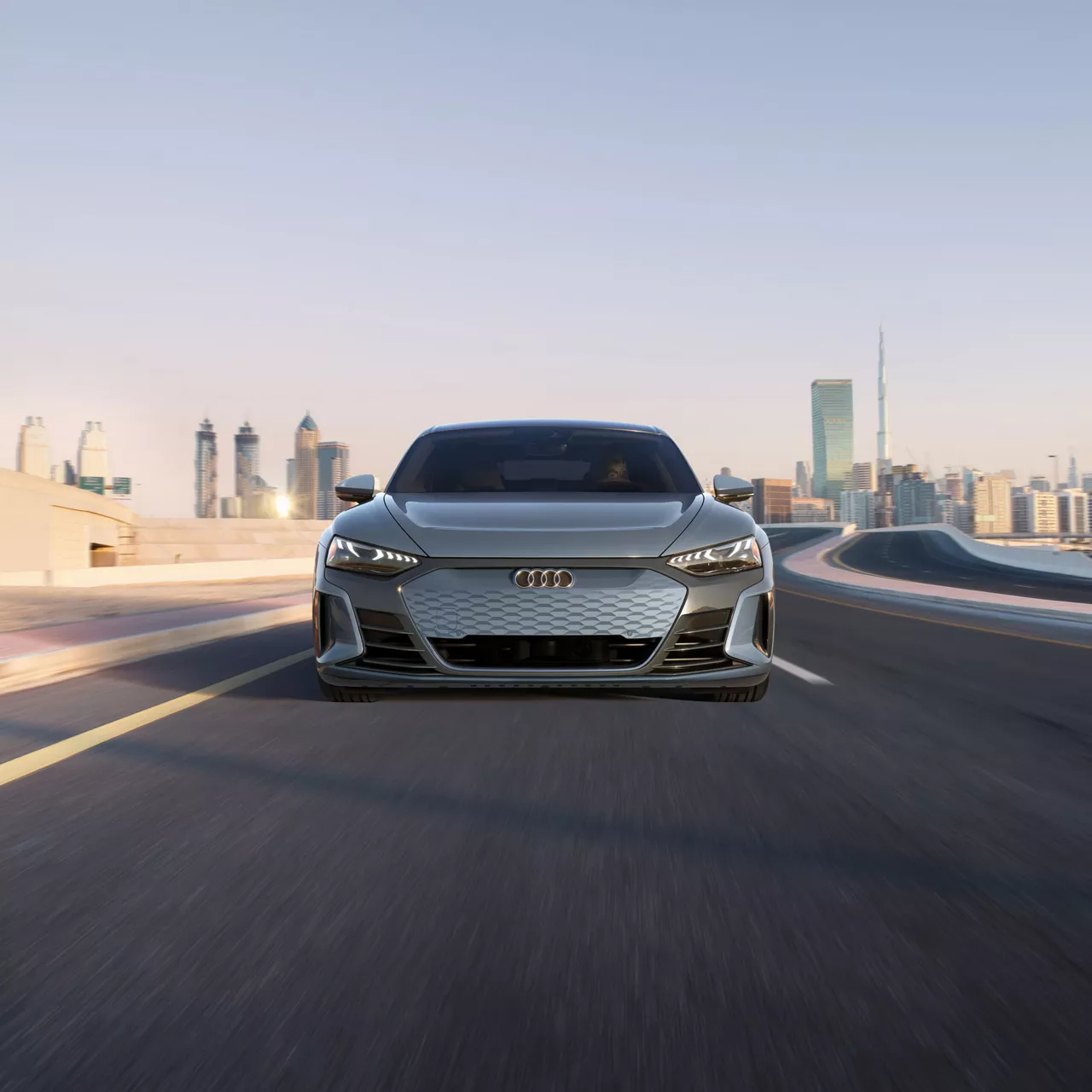 Front view of a gray Audi e-tron GT driving on a city road. 