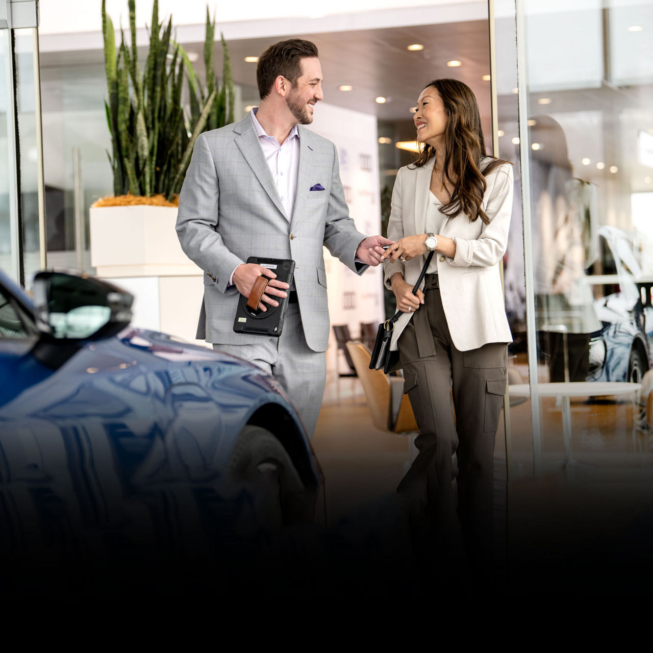 A smiling woman receiving the keys to her new Audi from the dealer. 