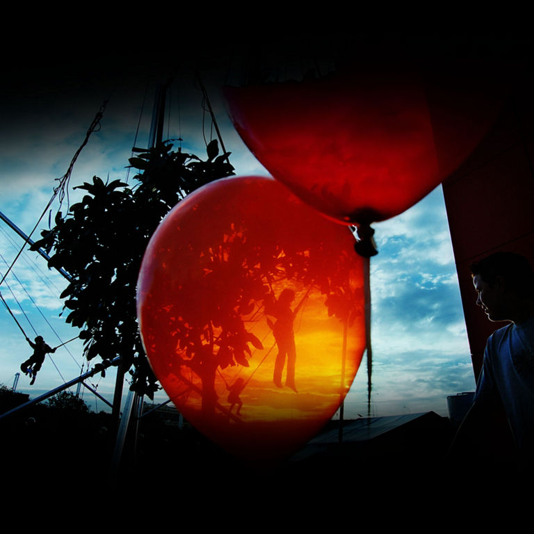 Image abstraite d’une silhouette féminine sur une tyrolienne vue à travers un ballon orange transparent.