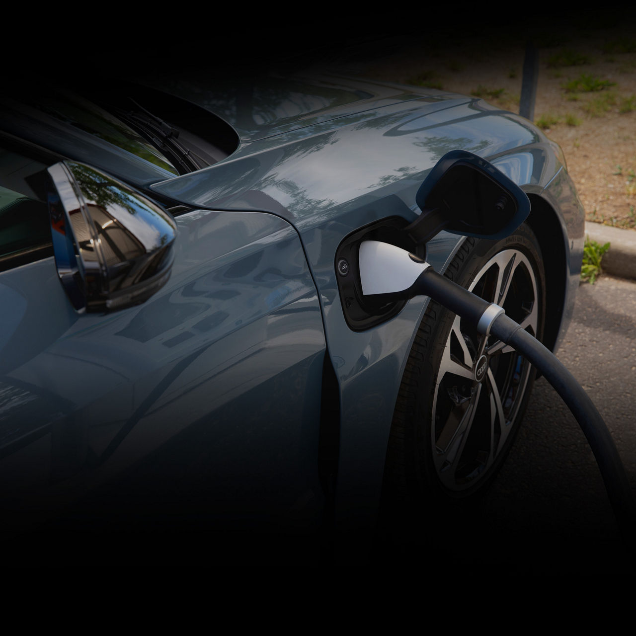 Close-up of a charging cord hooked up to the charging port of an Audi e-tron vehicle. 
