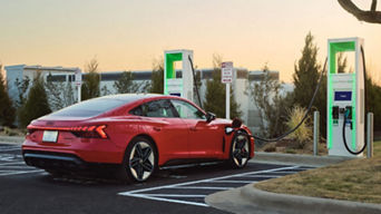 Three-quarter rear view of the Audi RS e-tron GT parked and charging at public charging unit.