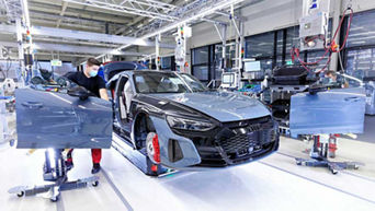 Front view of Audi technicians putting the doors on an Audi RS e-tron GT in an Audi manufacturing site.