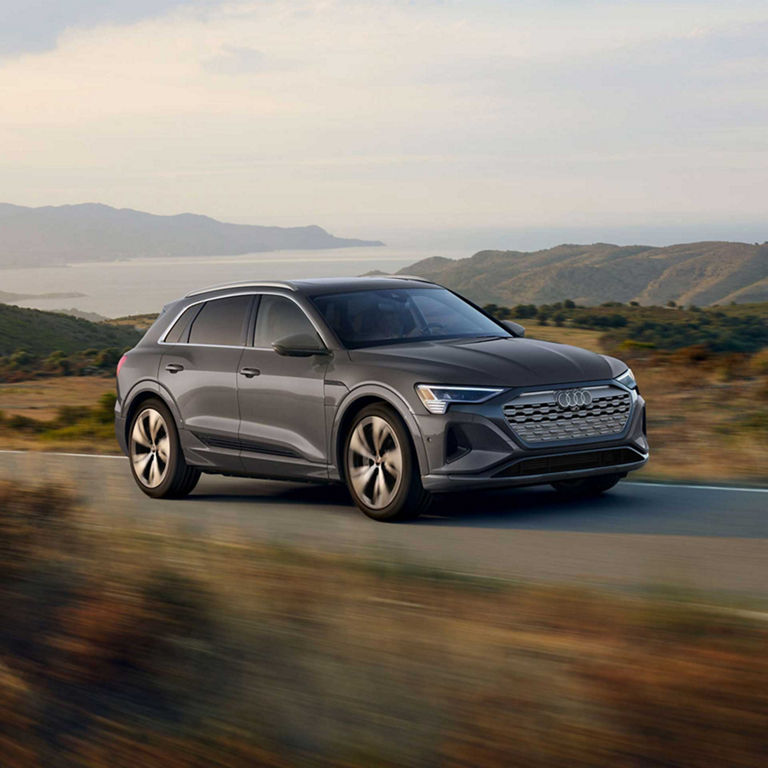 A grey Audi Q8 e-tron accelerating up a mountain road. 