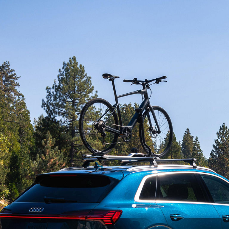 A bike strapped on to a bike rack on top of a blue Audi e-tron. 