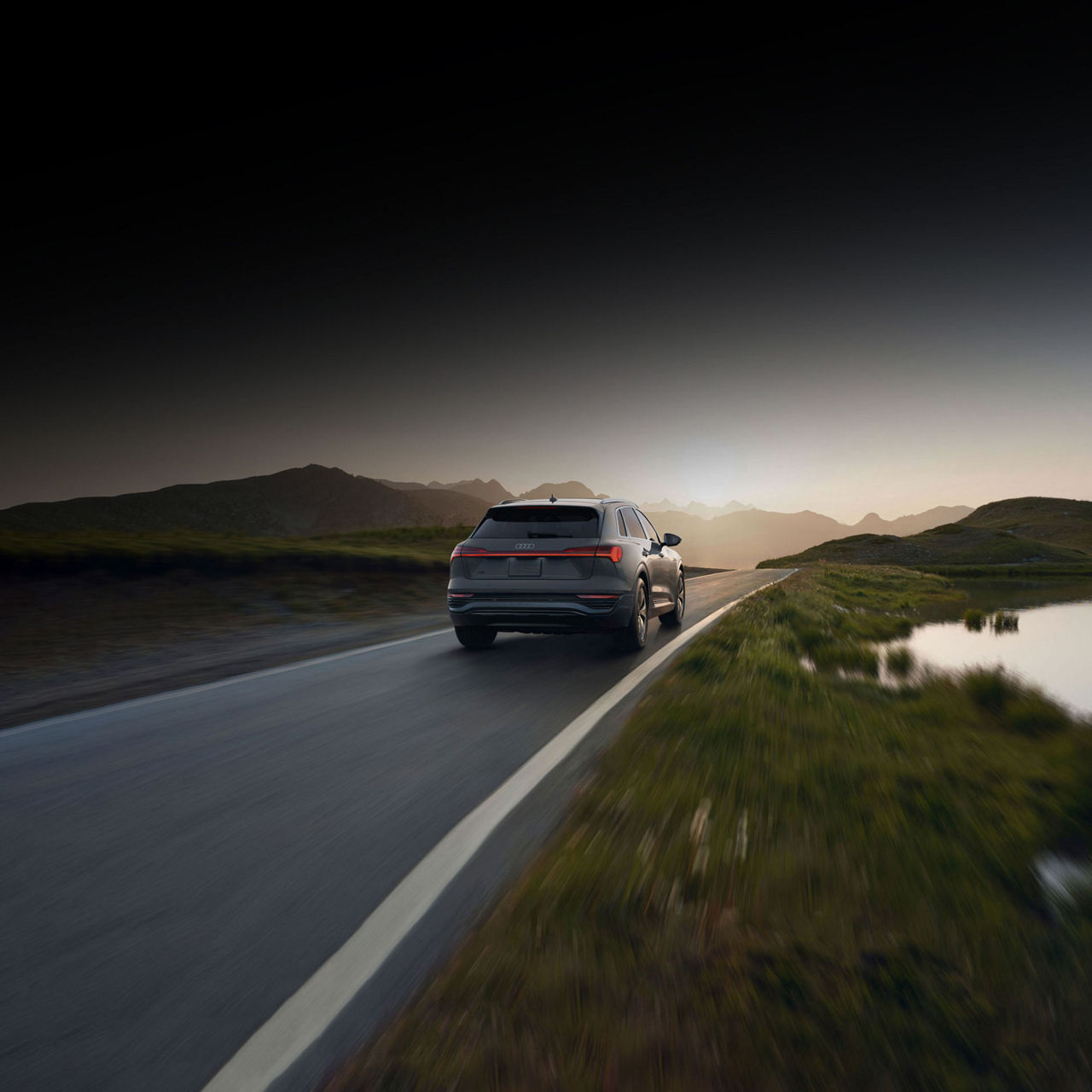 Rear view of an Audi Q8 e-tron driving on a mountain road. 
