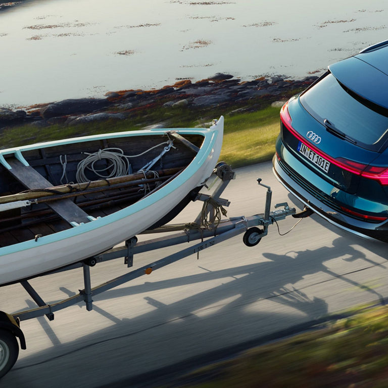 Bird's eye view of a blue Audi e-tron towing a boat. 