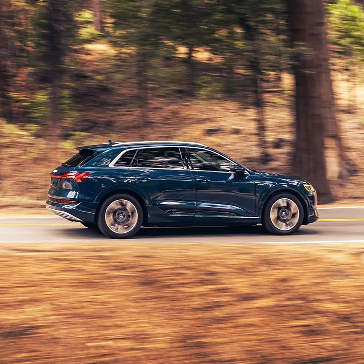 Side profile of the Audi e-tron® driving on a road.