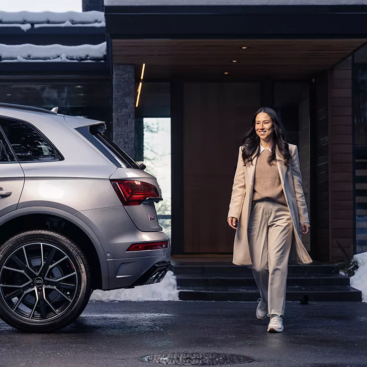 A woman standing next to a parked Audi SQ5. 