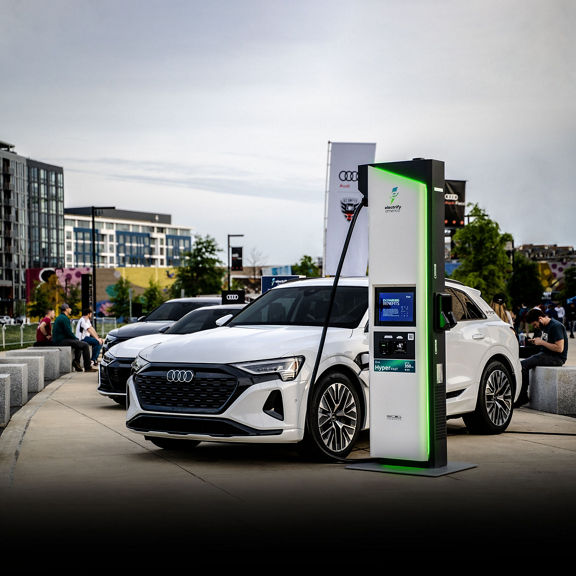 A white Audi Q8 e-tron hooked up to a charging station outside of Audi Field.