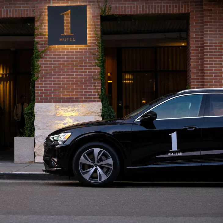 Side view of a black Audi vehicle with 1 Hotels decal parked in front of a 1 Hotel location.