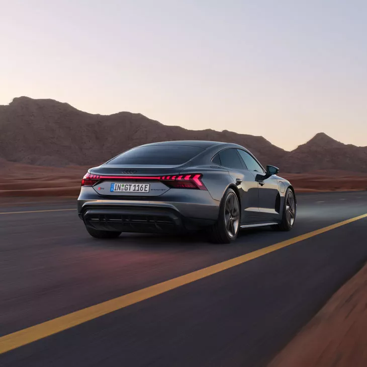 A grey Audi e-tron GT driving on a mountain road. 