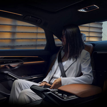 A woman seated in the back of an Audi A8, making use of the Rear matrix LED reading lights. 